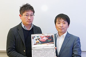 「ぐるなび外国語版」サイトを挟んで、（右）に水野氏、（左）に同システムの開発を指揮する久富謙介氏